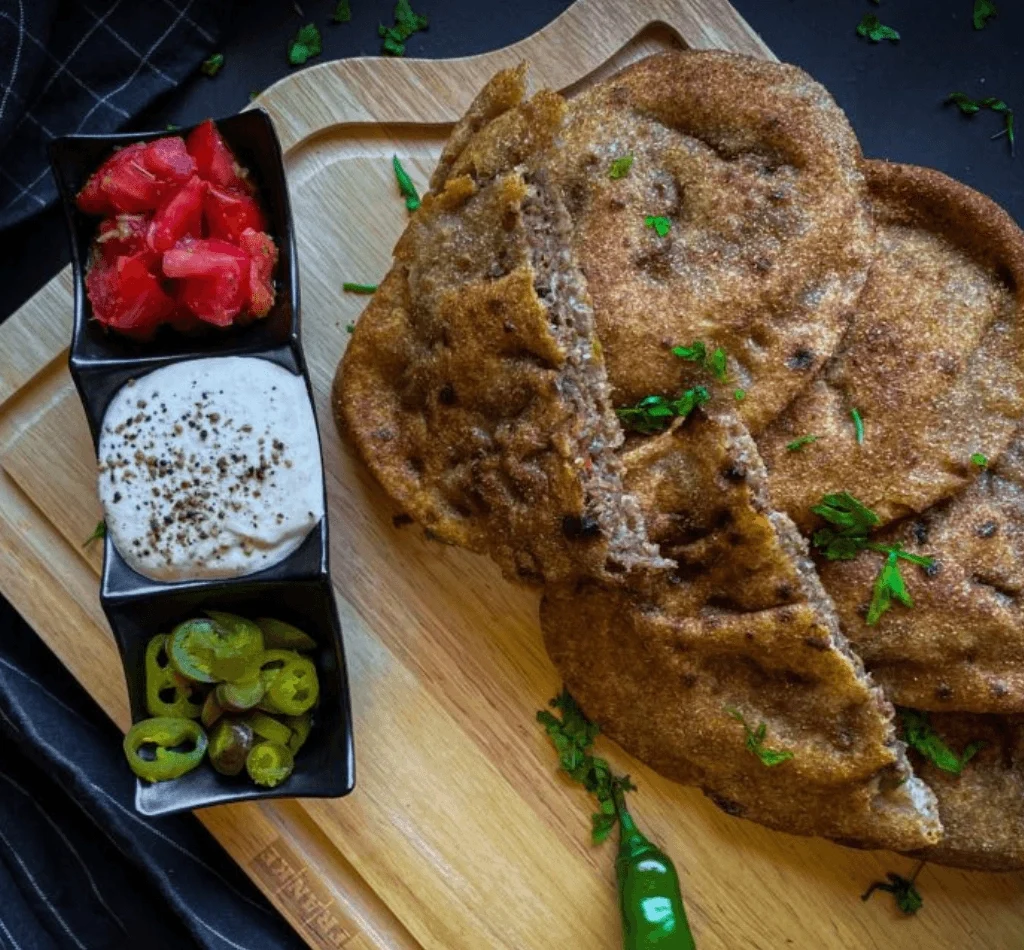 Traditional Egyptian food hawawshi stuffed bread with minced meat served with pickles and sauce