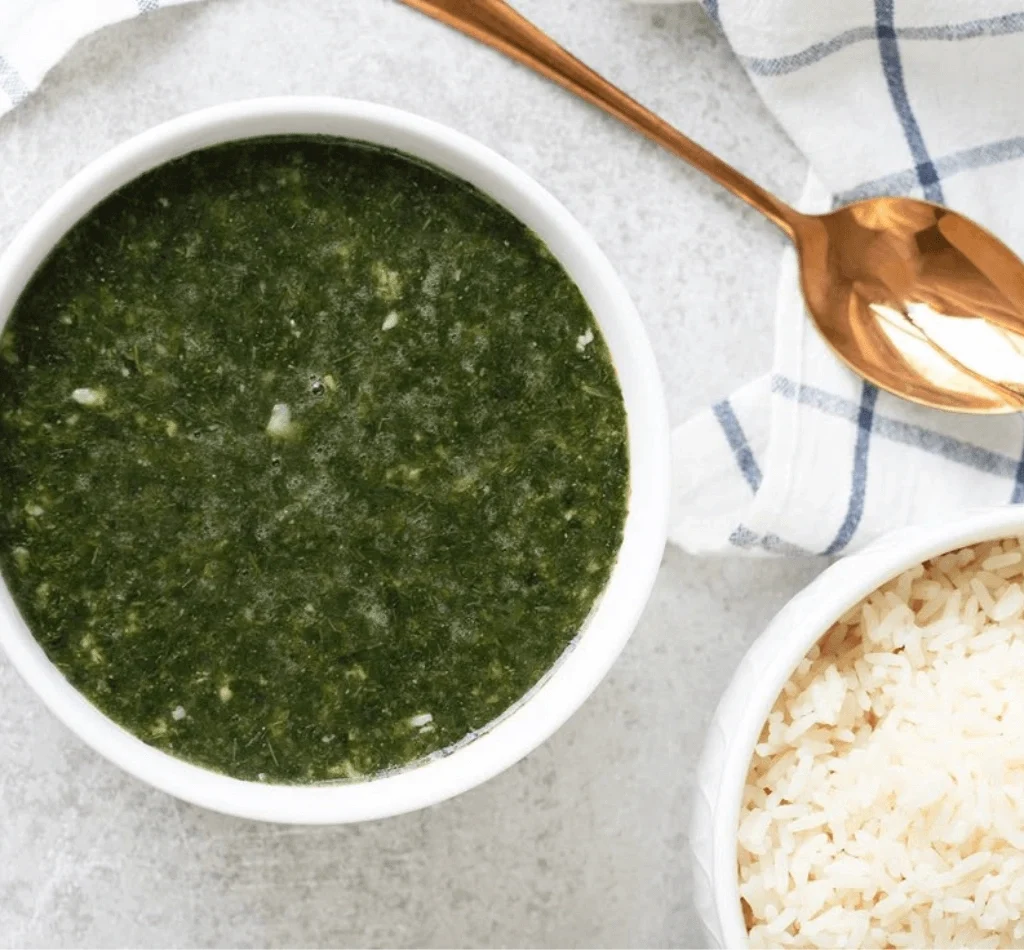 Traditional Egyptian food molokhia soup with rice served in bowl with spoon and cloth on table
