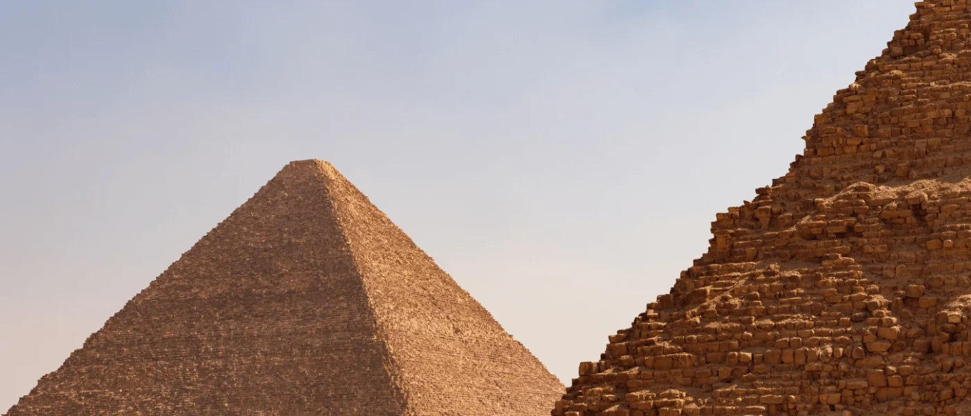 A close-up view of the stone blocks of the Great Pyramid with the Pyramid of Khafre in the background, a highlight of the best Egypt tour packages.