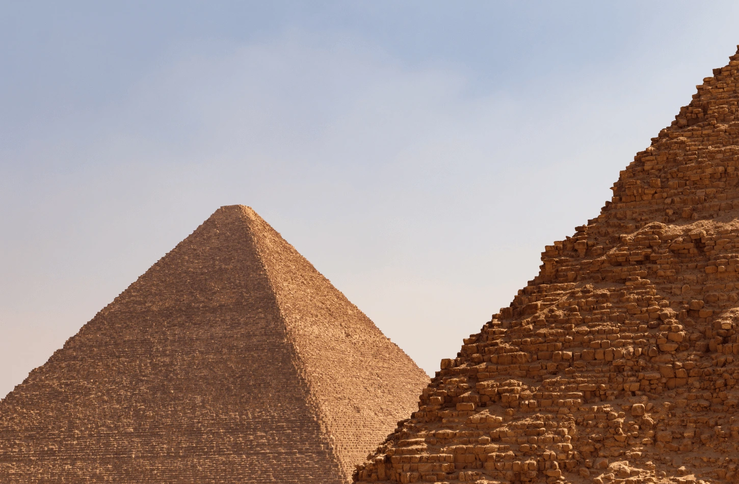 A close-up view of the stone blocks of the Great Pyramid with the Pyramid of Khafre in the background, a highlight of the best Egypt tour packages.