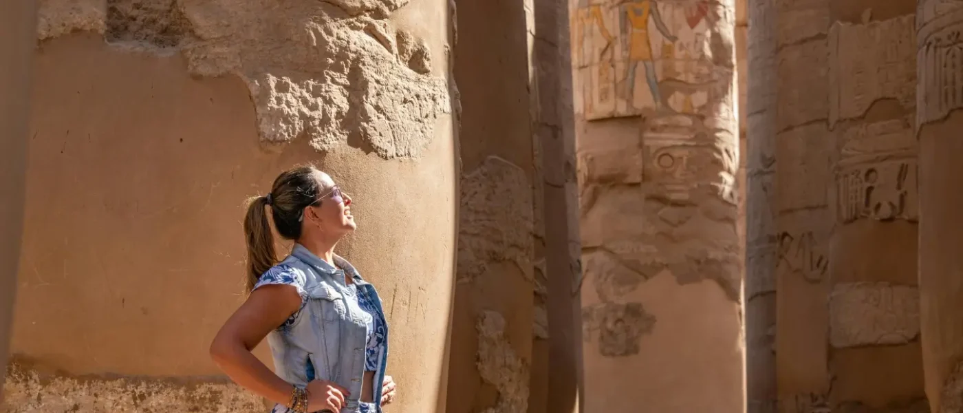 A female traveler looking up at the massive ancient columns and hieroglyphs of Karnak Temple in Luxor during a 14-day Egypt itinerary