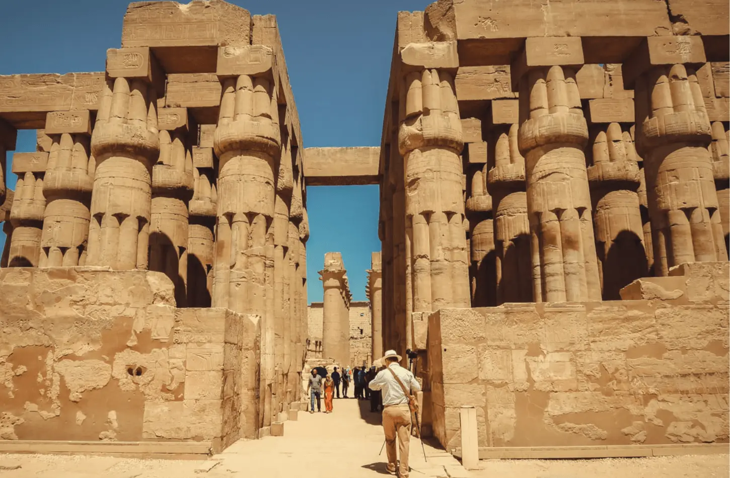 Tourists walking through the massive stone columns of the Great Hypostyle Hall at Karnak Temple Complex in Luxor, Egypt.