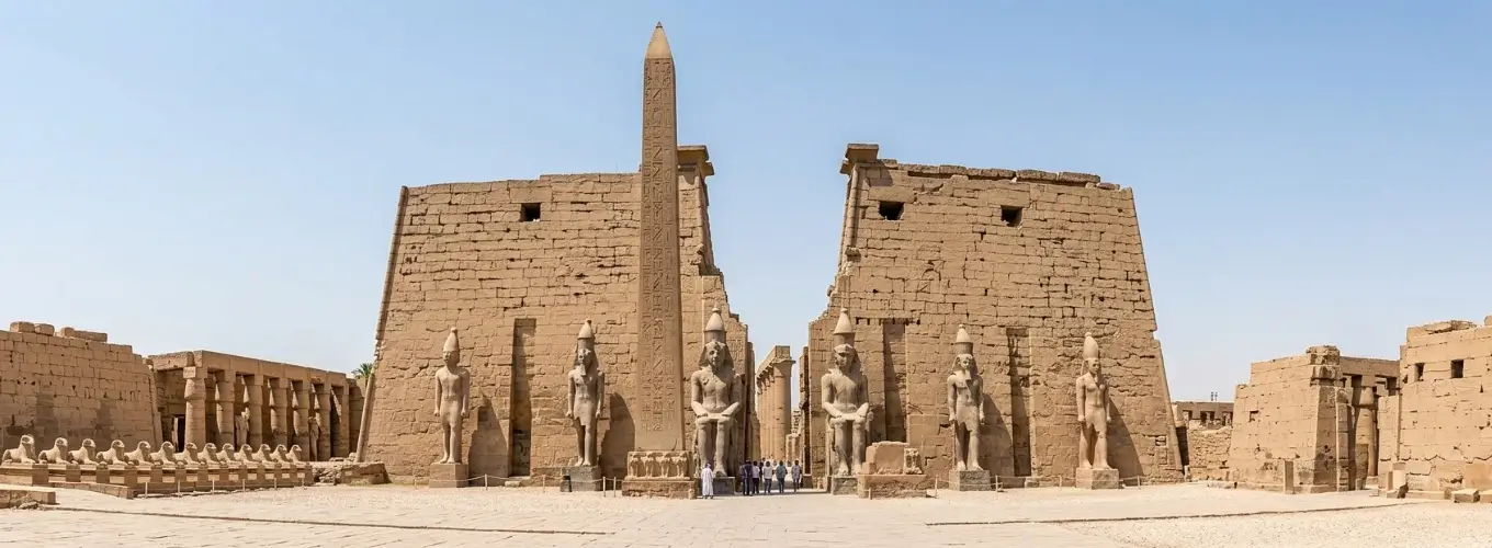 The grand entrance pylon, towering obelisk, and colossal stone statues of Ramesses II at Luxor Temple, representing the highlights of the Luxor East Bank.