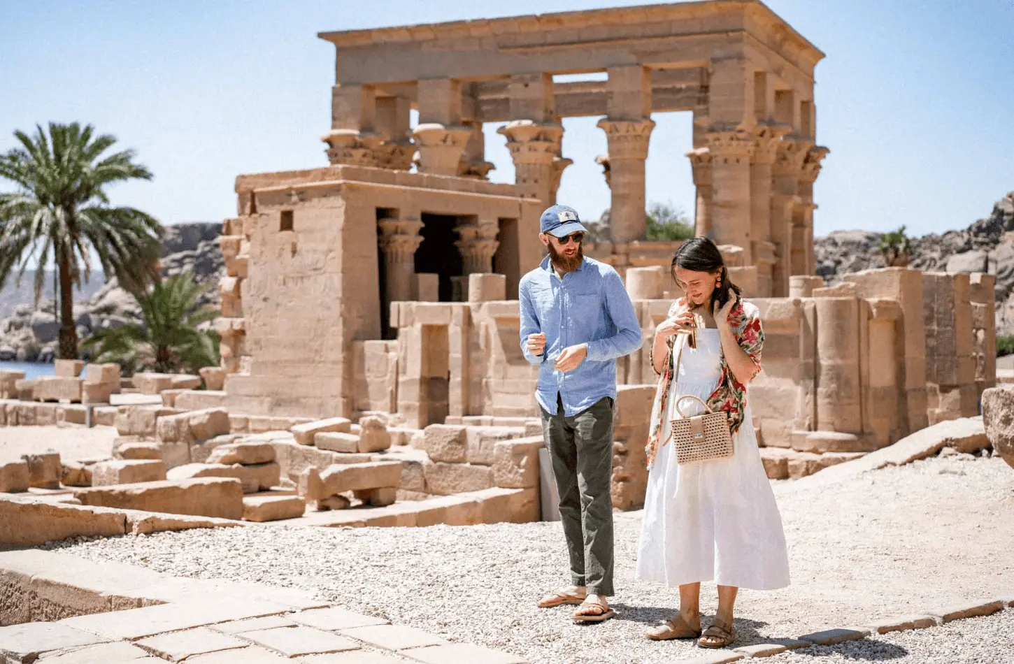 A man and woman standing in front of Trajan's Kiosk at the Philae Temple complex in Aswan, Egypt