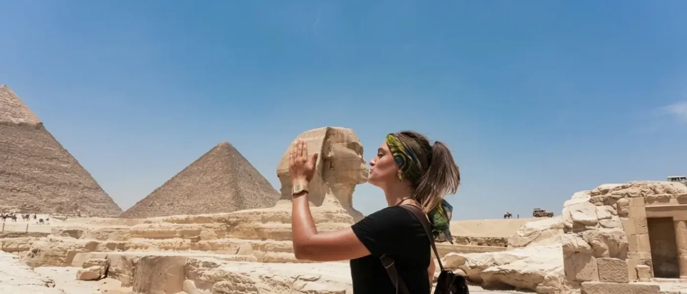 Tourist posing playfully in front of the Great Sphinx during a Pyramids of Giza tour with Egyptologist