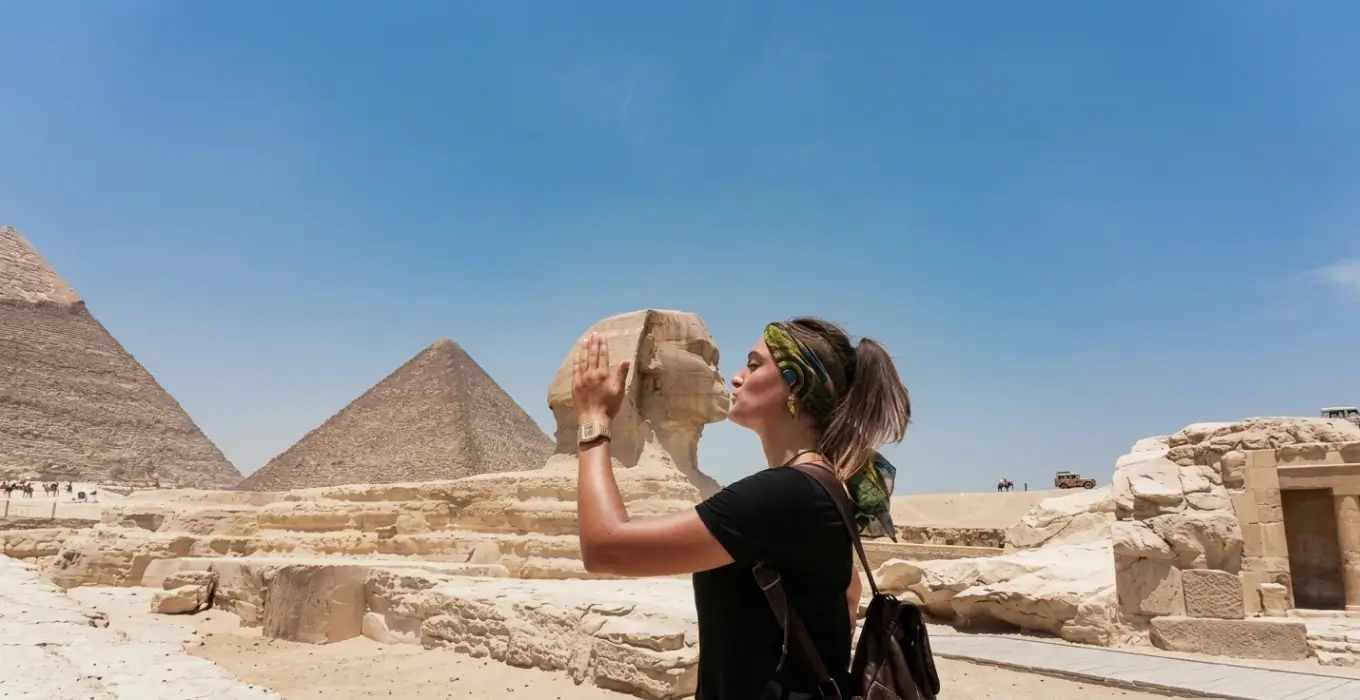 Tourist posing playfully in front of the Great Sphinx during a Pyramids of Giza tour with Egyptologist