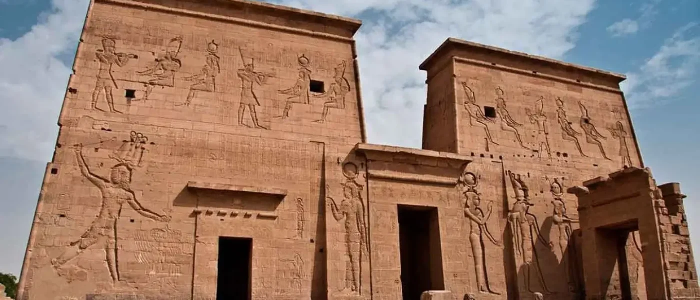 Philae Temple first pylon featuring ancient Egyptian relief carvings on large stone walls.