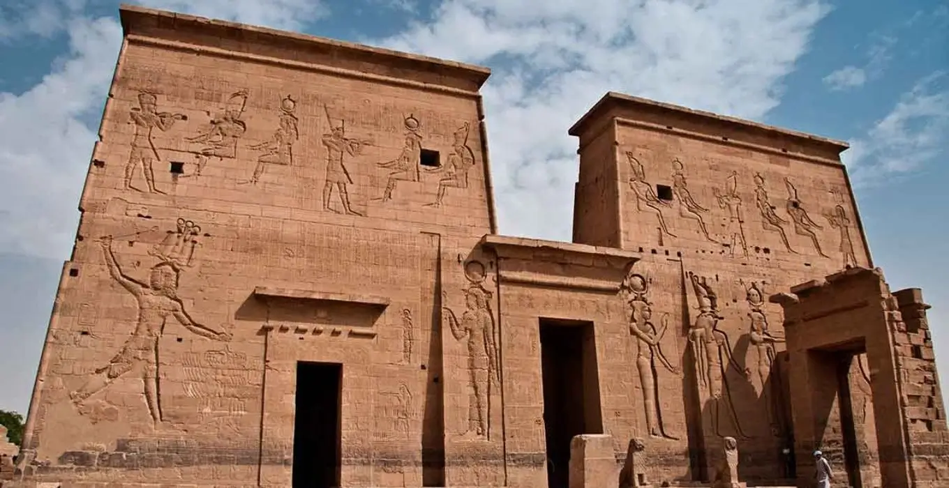 Philae Temple first pylon featuring ancient Egyptian relief carvings on large stone walls.