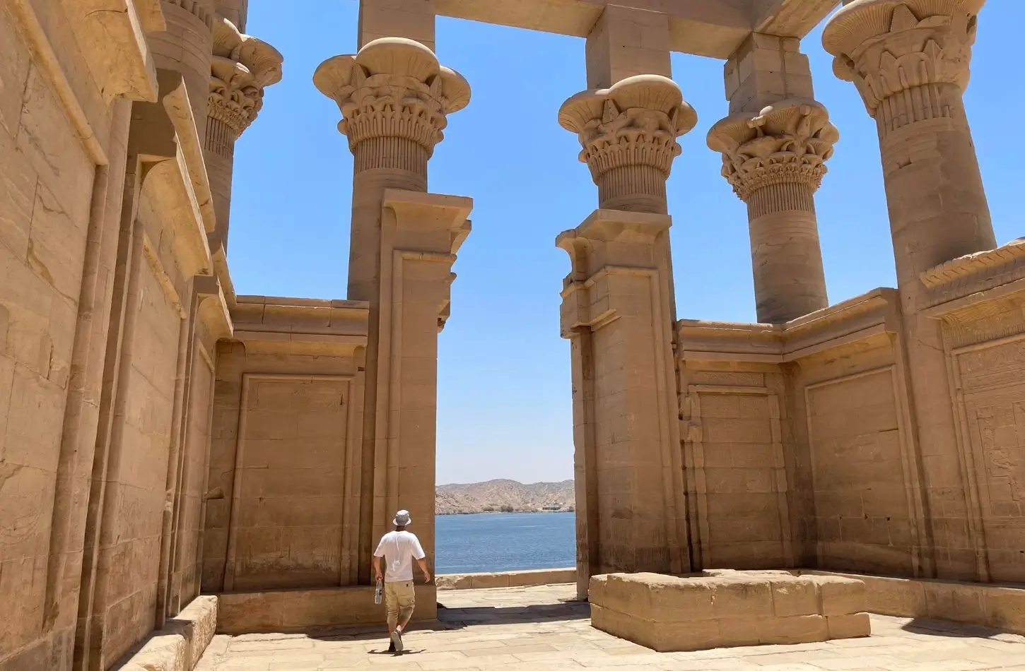 Philae Temple Trajan's Kiosk columns overlooking the blue waters of the Nile River in Aswan.