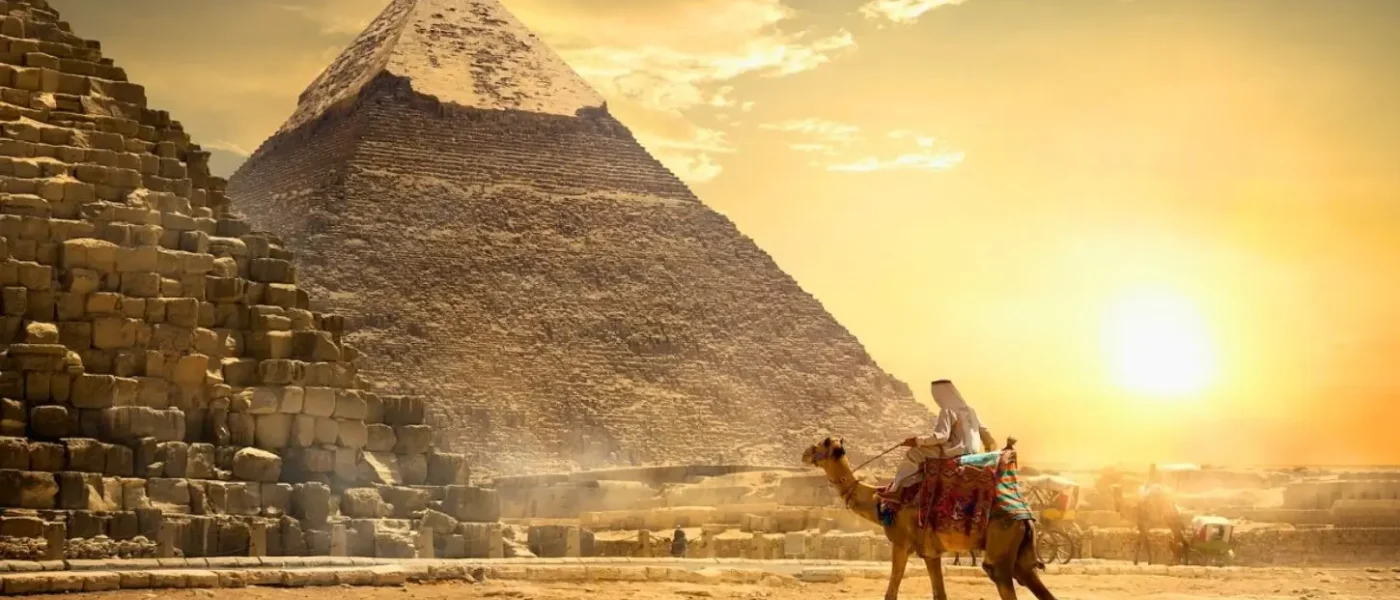Egypt in November offers ideal weather for exploring the Pyramids of Giza, where a traveler on a camel rides past the ancient stone monuments at sunset.