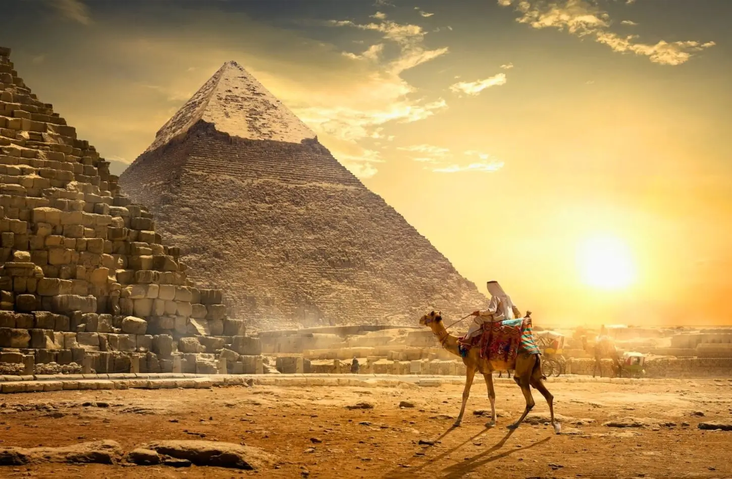 Egypt in November offers ideal weather for exploring the Pyramids of Giza, where a traveler on a camel rides past the ancient stone monuments at sunset.