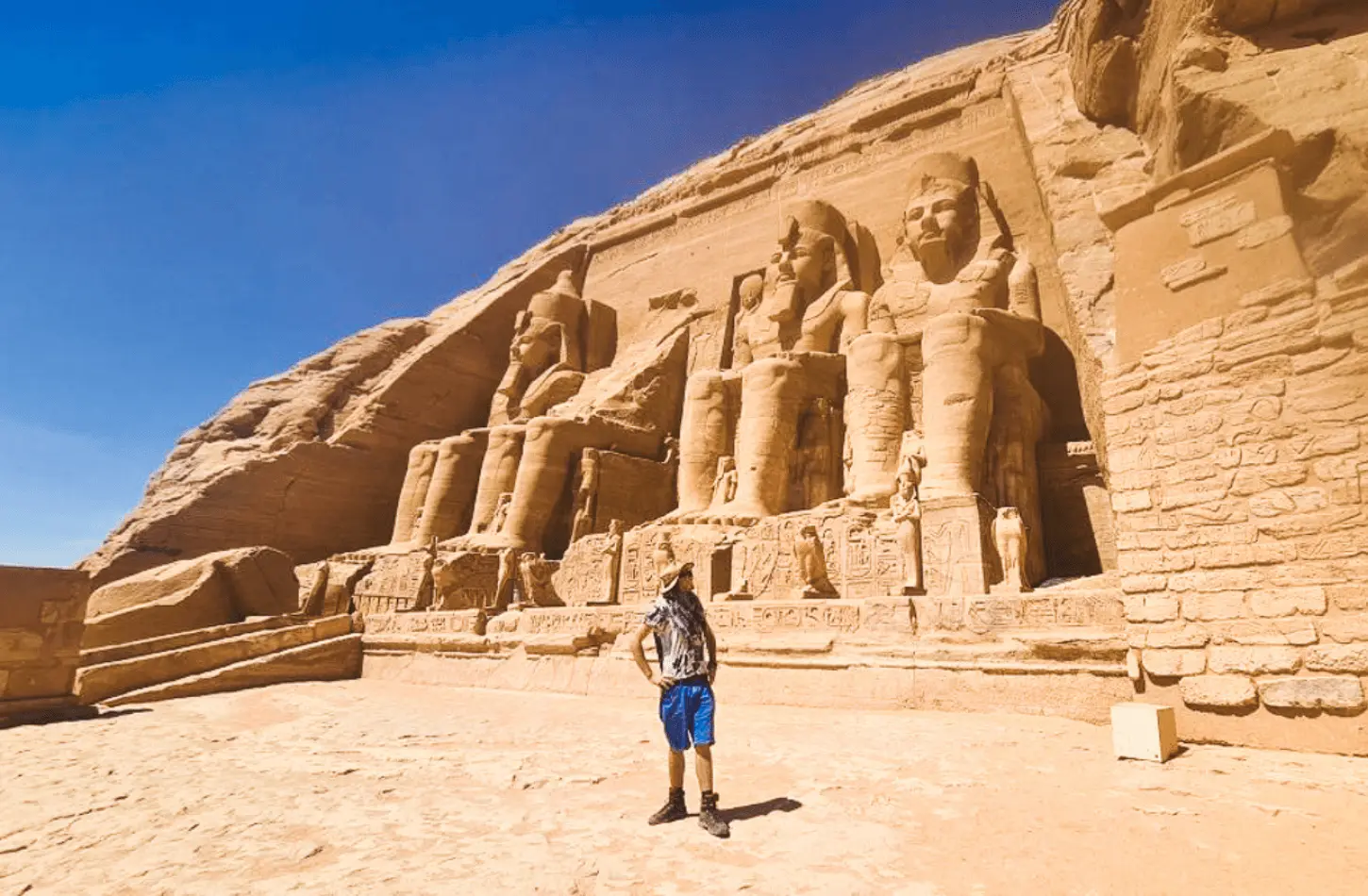 A traveler standing in front of the colossal stone statues at Abu Simbel Temple, illustrating how to travel Egypt on a budget.