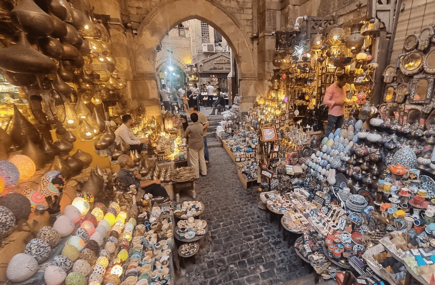 A bustling alleyway in Khan el-Khalili bazaar filled with glowing lanterns and souvenirs, perfect for travelers learning how to travel Egypt on a budget.