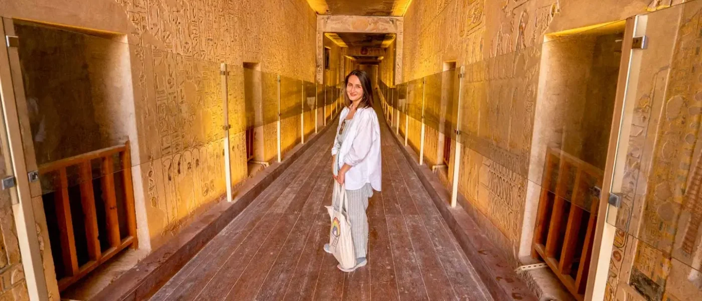 A-woman-standing-in-a-corridor-inside-an-ancient-egyptian-tomb-with-hieroglyphs-on-the-walls