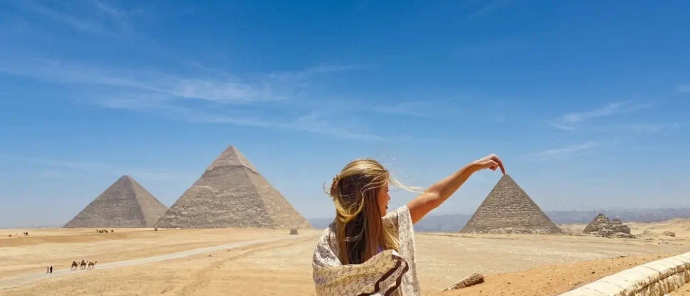 Female tourist enjoying clear blue weather at the Pyramids of Giza during the best time to visit Egypt