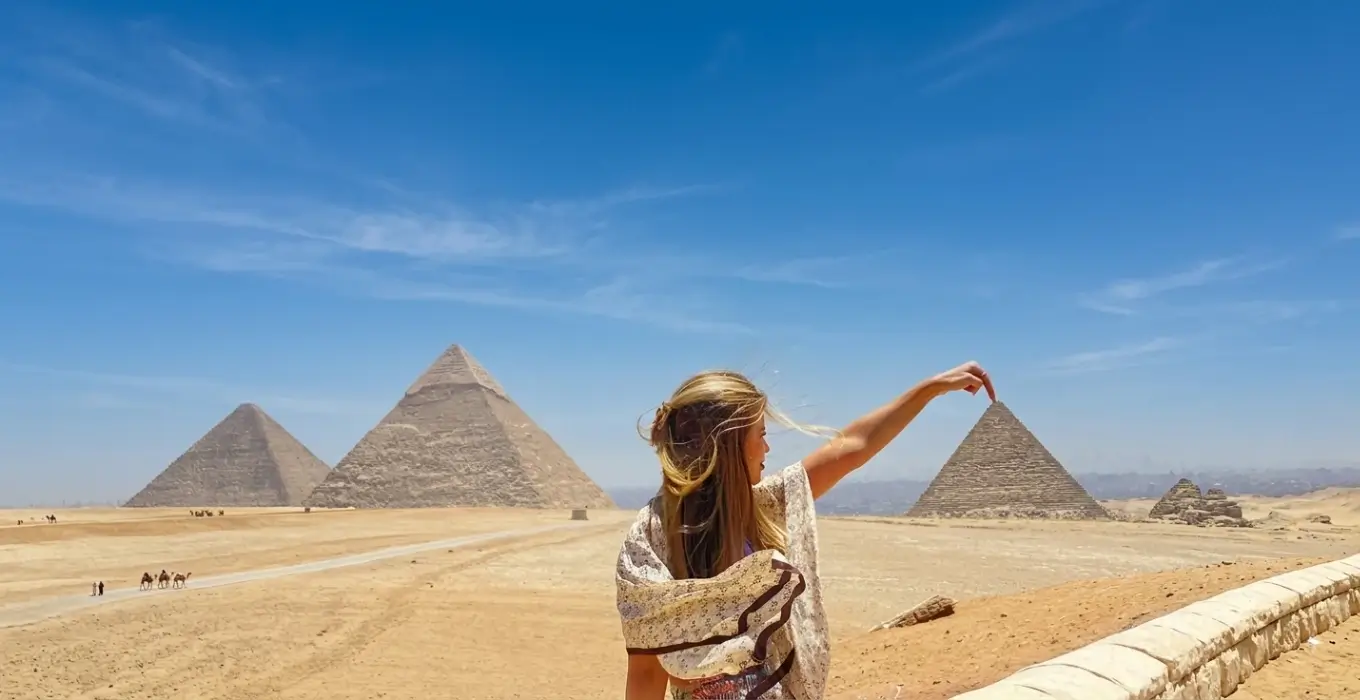 Female tourist enjoying clear blue weather at the Pyramids of Giza during the best time to visit Egypt